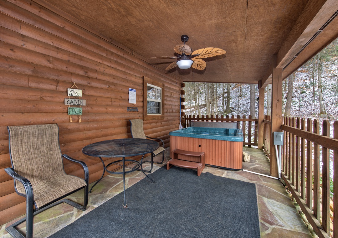 Unwind on your private covered deck with bubbling hot tub and cozy seating, surrounded by peaceful wooded views.