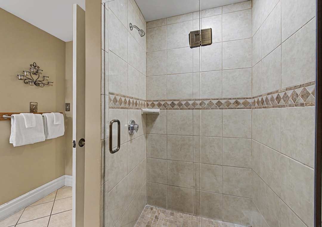 Your spacious walk-in shower features elegant tiled walls and mosaic accents, creating a spa-like retreat for your daily refresh.