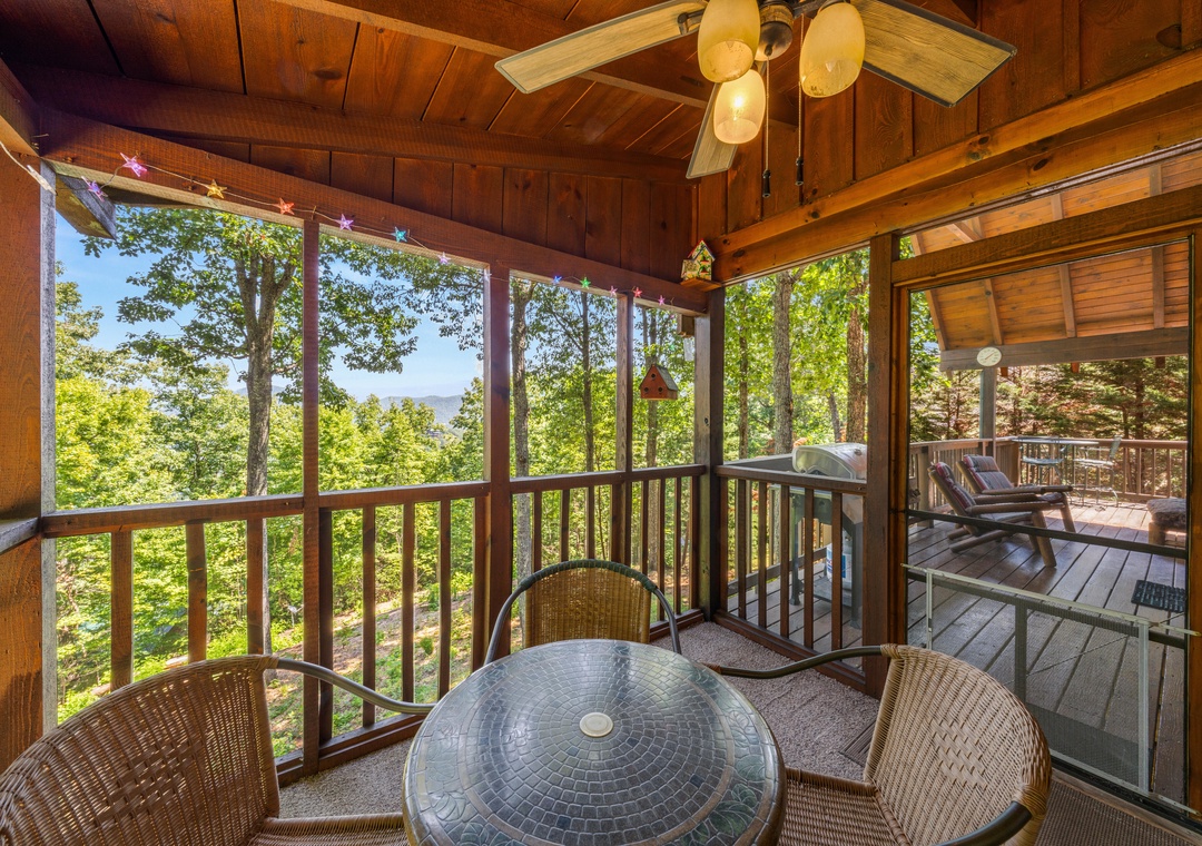 Picture yourself sipping morning coffee at this screened porch table, surrounded by warm wood and lush treetops, with serene lake views stretching beyond. Your peaceful retreat awaits.