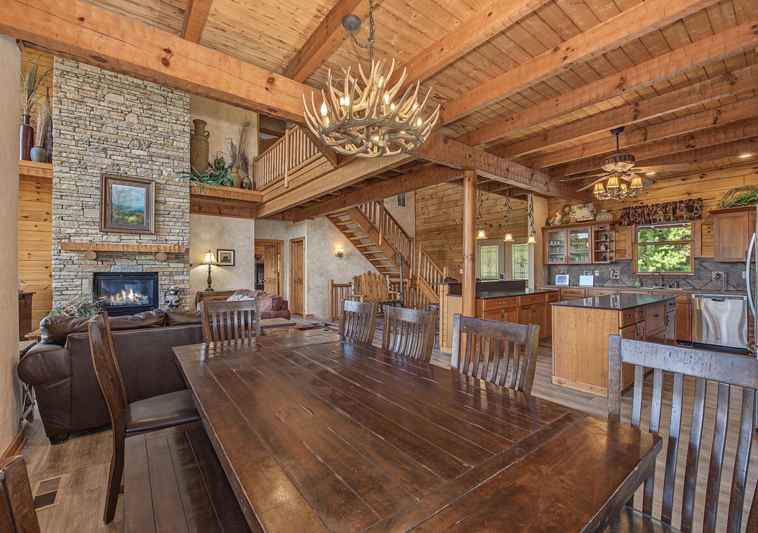 Gather around the handcrafted dining table beneath a stunning antler chandelier, where rustic elegance meets open-concept living. Natural wood, a stone fireplace, and fully-equipped kitchen create the perfect mountain retreat.