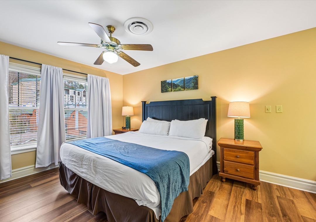 Wake up refreshed in your cozy bedroom with plush bedding, warm lighting, and peaceful street views through large windows.