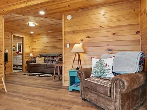 Relax in your spacious cabin retreat featuring warm knotty pine walls, plush leather seating, and abundant natural light. Your cozy living area flows seamlessly into additional spaces, offering plenty of room to unwind.
