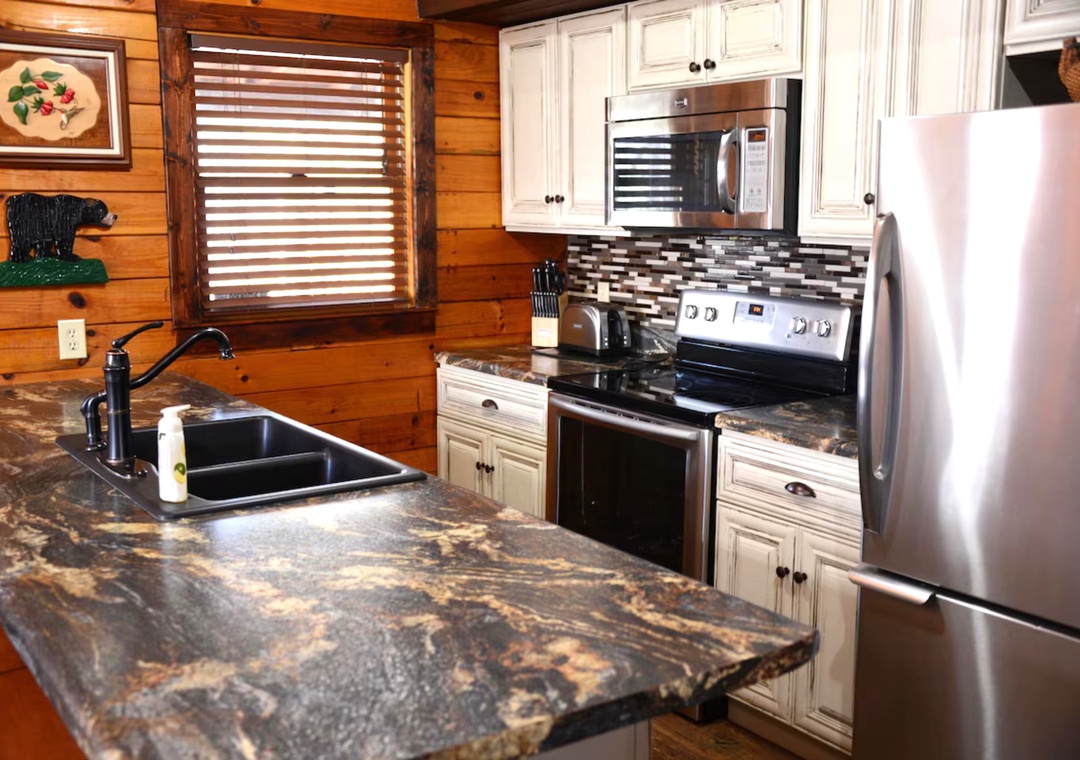 Your fully equipped cabin kitchen features granite countertops, stainless appliances, and warm wood walls for memorable mountain meals.