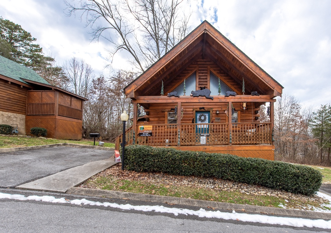 A charming log cabin retreat nestled among tall trees, featuring a welcoming front porch and rustic wood exterior in a peaceful wooded setting.