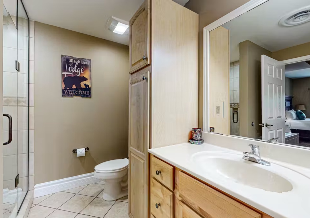 Your private bathroom features a spacious walk-in shower and warm wood vanity, creating a cozy retreat for your morning routine.