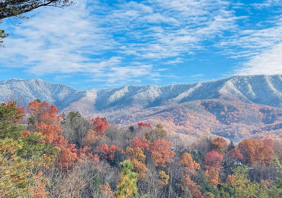 Stunning mountain vista where autumn foliage meets the first dusting of winter snow, creating a picturesque backdrop for the property's scenic location.