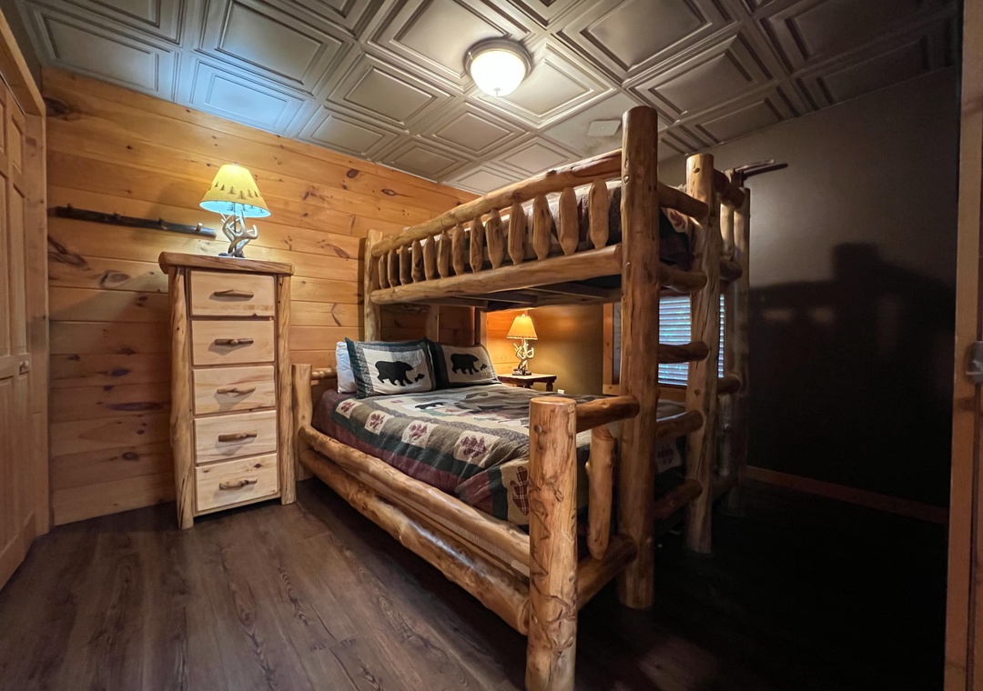 Your rustic retreat features handcrafted log bunk beds with charming wildlife bedding, warm wood paneling, and elegant coffered ceilings—perfect for family memories in a cozy mountain escape.
