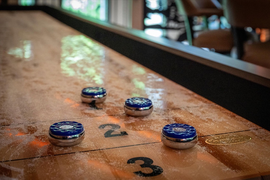Ready for your next game? This classic shuffleboard table awaits, polished and prepped for friendly competition in your cozy game room retreat.