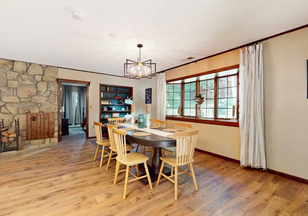 Gather around this warm dining space with rustic charm, where wooden chairs and stone fireplace create the perfect setting for your memorable meals together.
