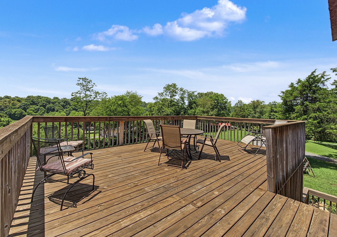 Expansive deck overlooking lush greenery and open lawn. Perfect for your morning coffee or evening gatherings with multiple seating areas to relax and soak in the natural surroundings.