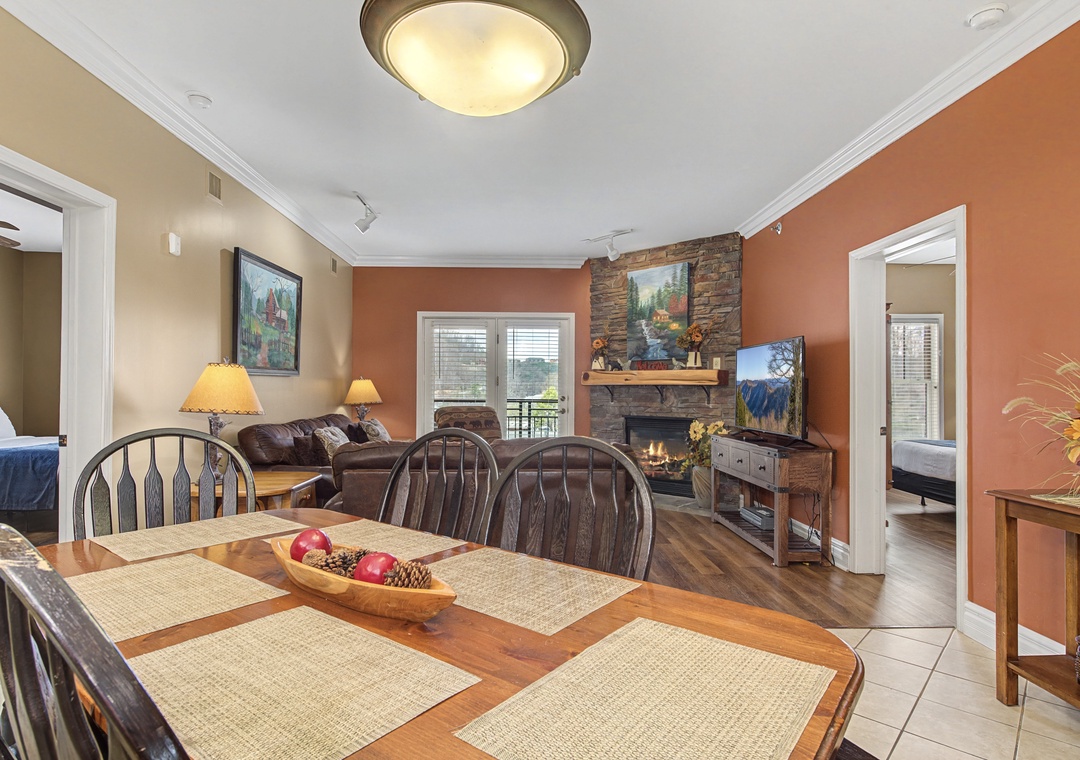 Your cozy dining space flows seamlessly into the living room, where warm autumn colors and a stone fireplace create the perfect atmosphere for memorable meals together.