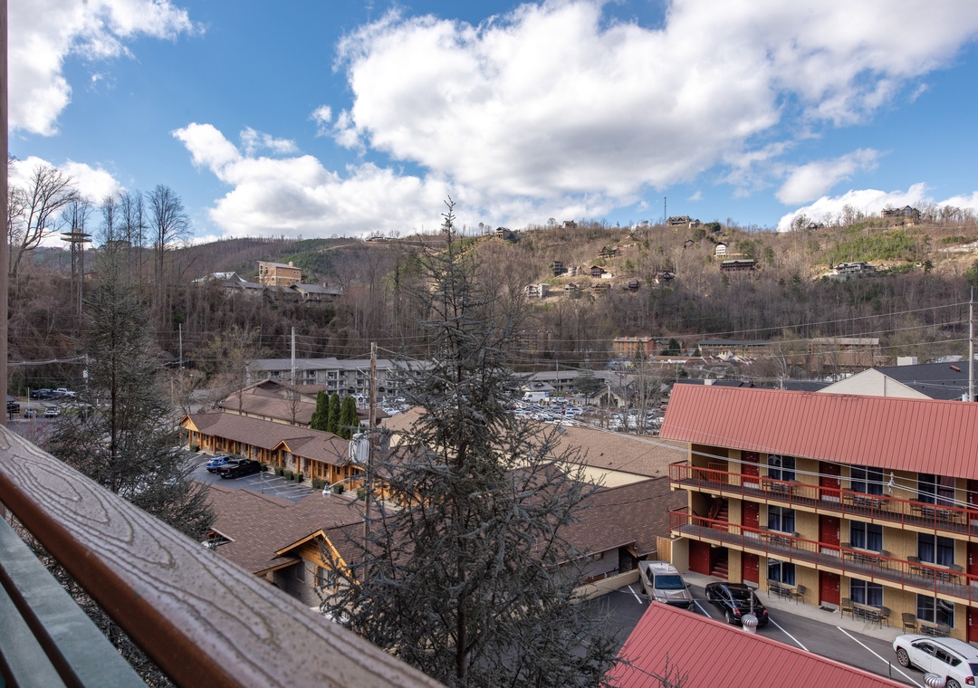 Mountain town panorama spreads below with rolling hills and scattered homes creating a peaceful valley setting.