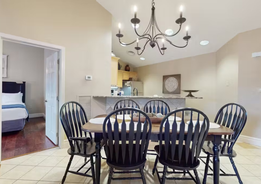Gather around your elegant dining table under warm chandelier lighting, with the kitchen just steps away for easy entertaining.