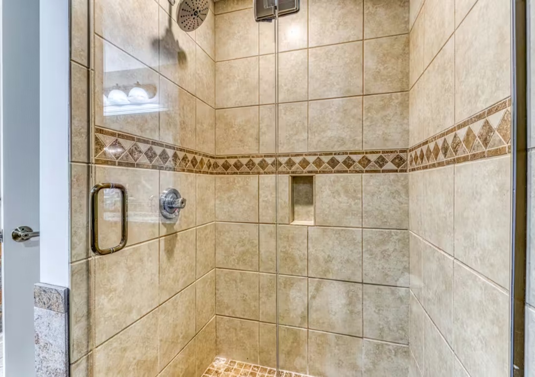 Step into your beautifully tiled shower with elegant stonework and rainfall showerhead for refreshing mornings.