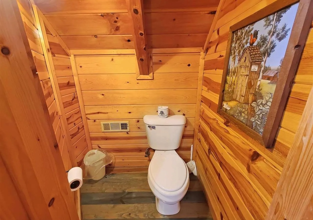 Step into your private rustic bathroom, where warm cedar walls and charming country artwork create a cozy mountain retreat atmosphere.