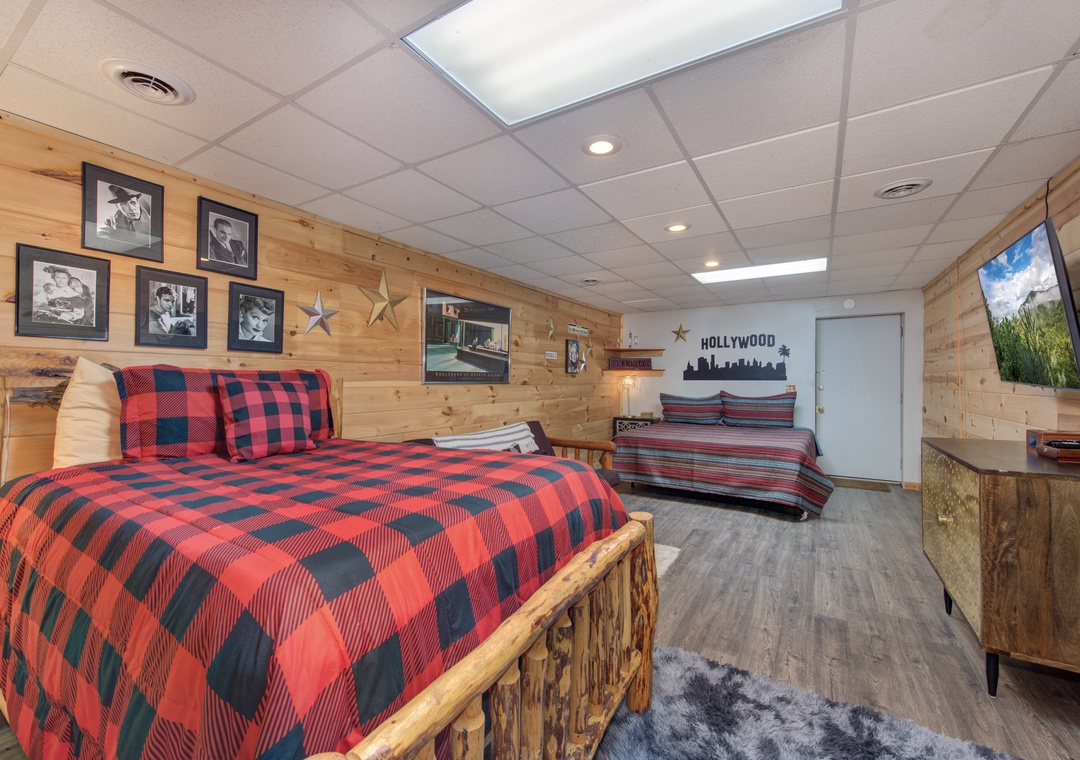 Cozy up in your rustic bedroom featuring beautiful wood walls, plaid bedding, and entertainment center for relaxing movie nights.