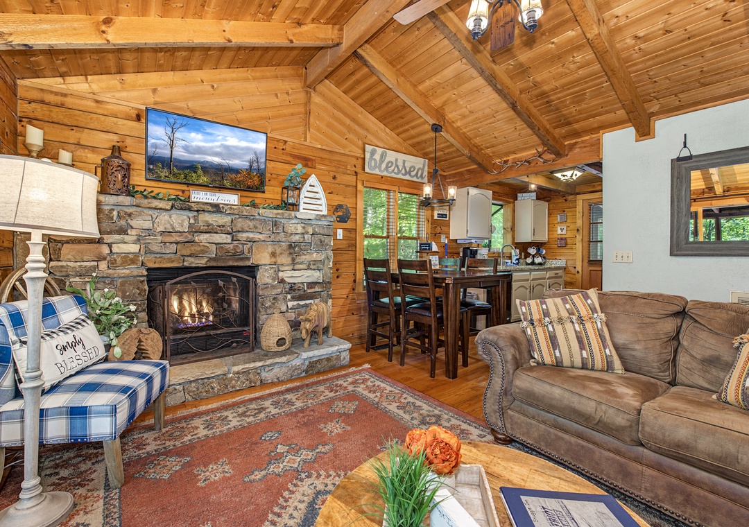 Settle into your cozy living area where rustic wood beams and a warm stone fireplace create the perfect mountain retreat atmosphere for relaxing evenings together.