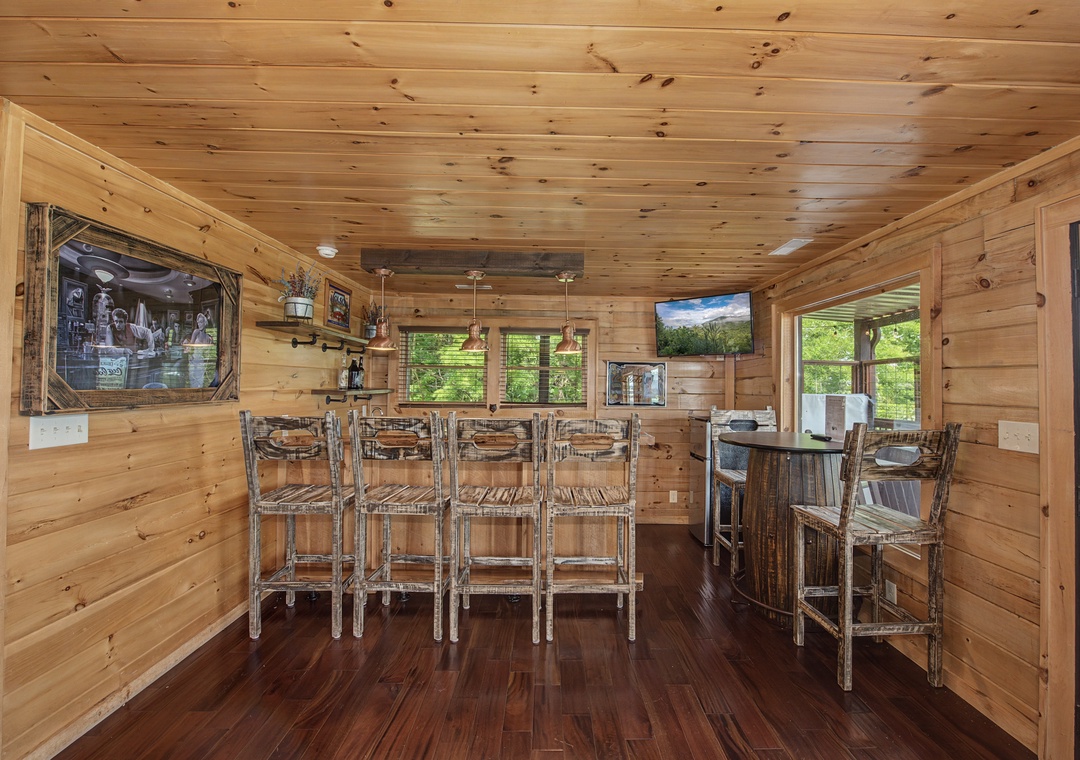 Your private bar area features rustic wood seating, flat-screen TVs, and warm natural light—perfect for unwinding with friends or enjoying a game night in pure mountain cabin style.