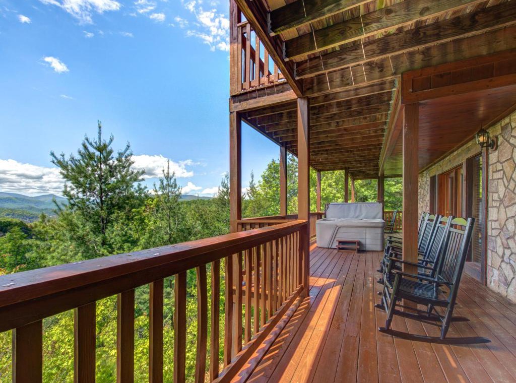 Unwind on your private mountain retreat deck with rocking chairs and sofa, where forest views stretch endlessly before you.
