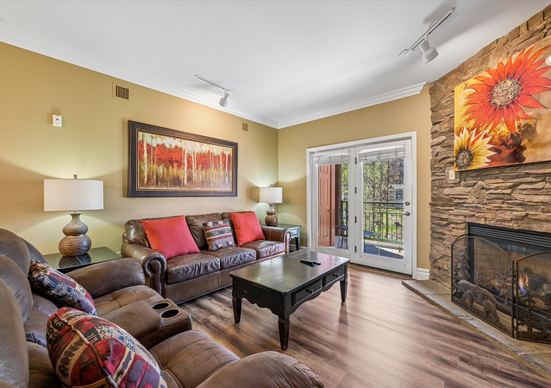 Unwind in your cozy living room featuring plush leather seating, a crackling fireplace, and private balcony access for mountain air.