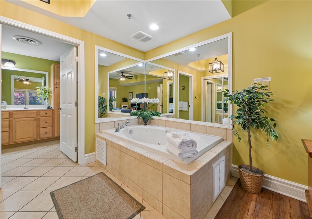 Unwind in your private spa-like bathroom featuring a luxurious jetted tub surrounded by warm colors and tropical plants.