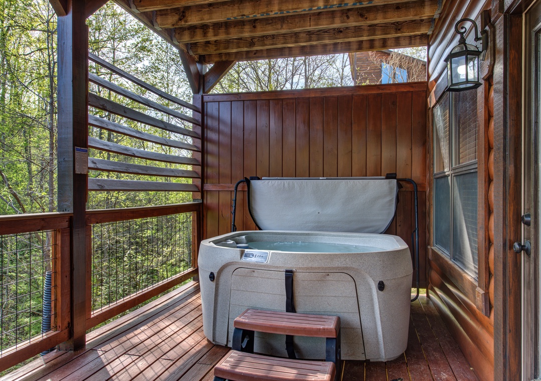 Soak in your private hot tub on the covered deck, surrounded by lush forest views and rustic wood details.