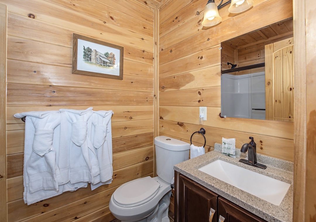 Freshen up in your cozy cabin bathroom, featuring a granite vanity, plush towels, and rustic wood walls that create a warm mountain retreat feel.