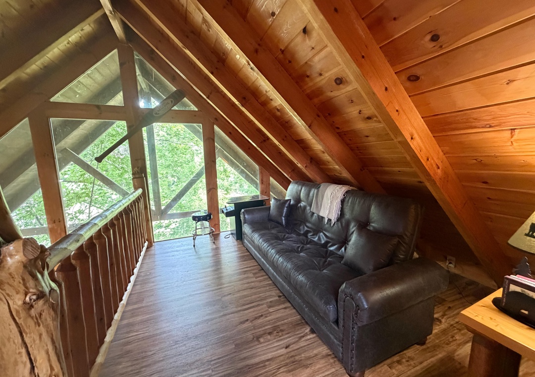 Settle into the leather sofa under vaulted wood ceilings and let natural light pour through the glass doors opening to your private deck, surrounded by lush greenery.