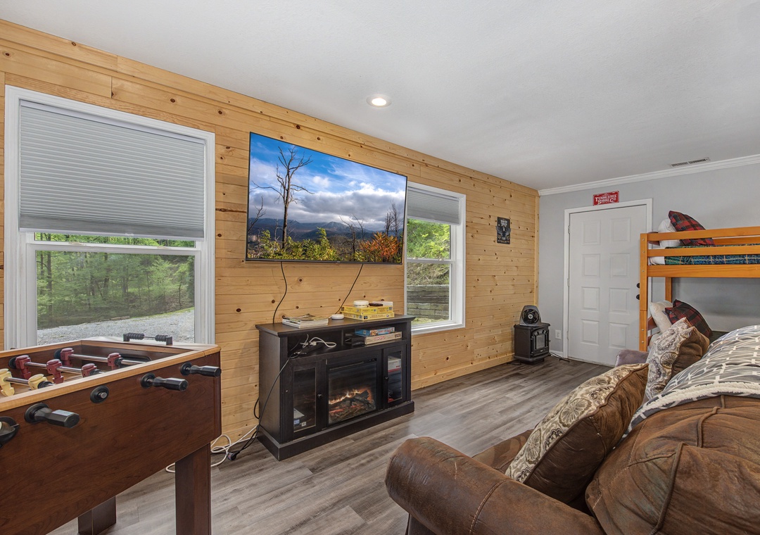 Unwind in your cozy game room featuring foosball, fireplace warmth, and mountain views through large windows.