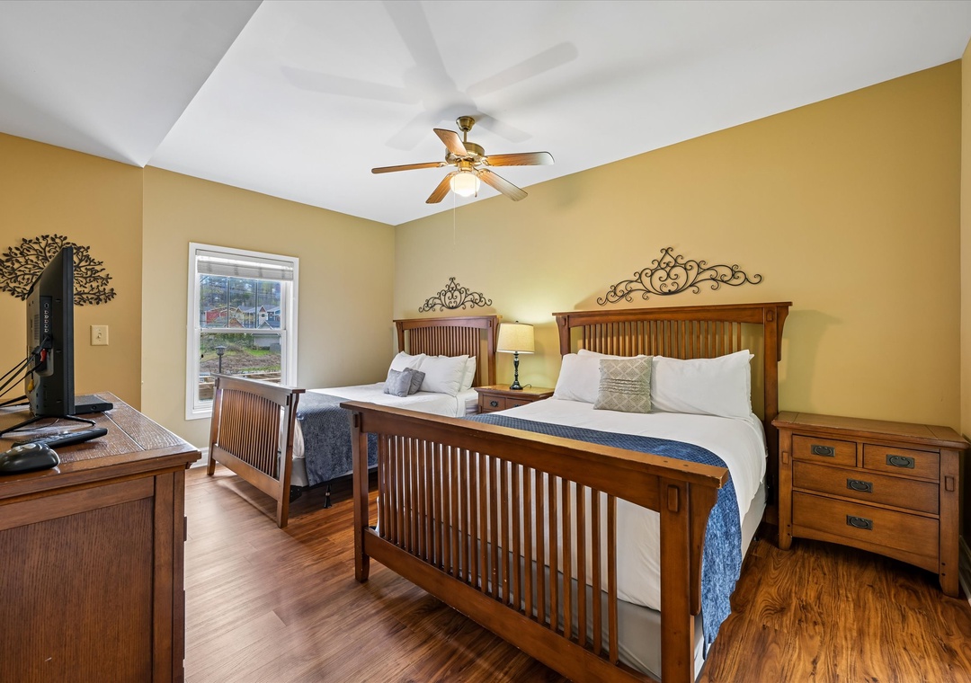 Relax in your spacious bedroom featuring handcrafted Mission-style twin beds with crisp linens, hardwood floors, and a ceiling fan for comfort.