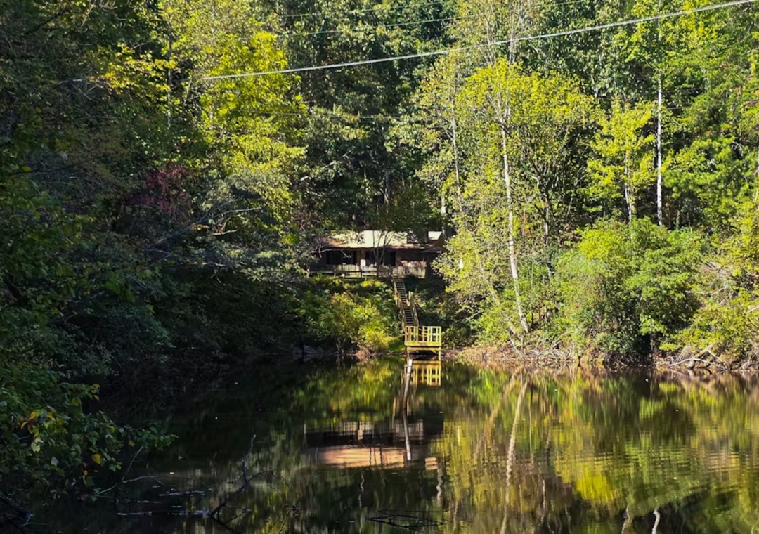 A charming lakefront retreat nestled among vibrant spring foliage, with a private dock reflecting perfectly in the tranquil waters.