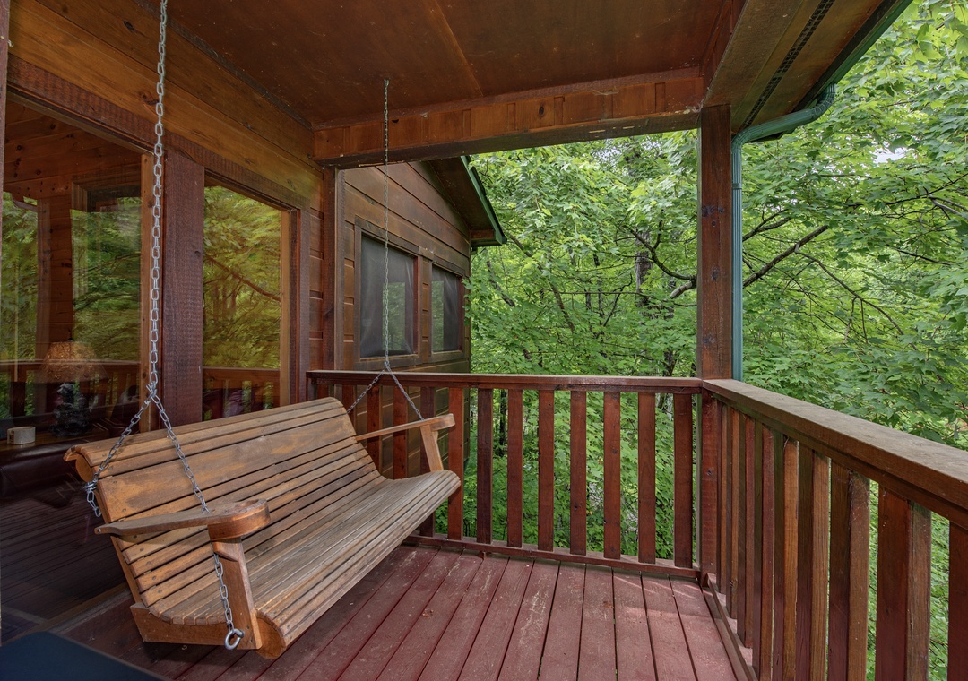Swing gently and soak in lush forest views from your private covered porch, where the trees create a peaceful, natural canopy just beyond the railing.