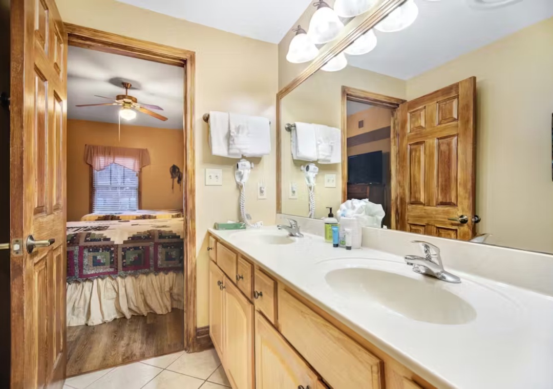 Step into your spacious bathroom with dual sinks and warm wood accents, connecting to your cozy bedroom retreat.