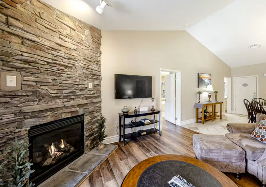 Unwind in your cozy living space featuring a stunning stone fireplace, flat-screen TV, and comfortable seating perfect for relaxing evenings together.