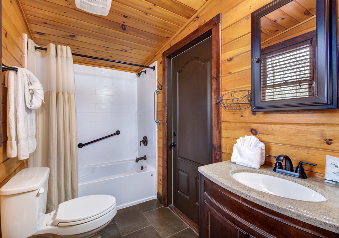 Unwind in your private bathroom featuring rustic wood walls, a deep soaking tub, and all the comforts you need for a refreshing retreat.