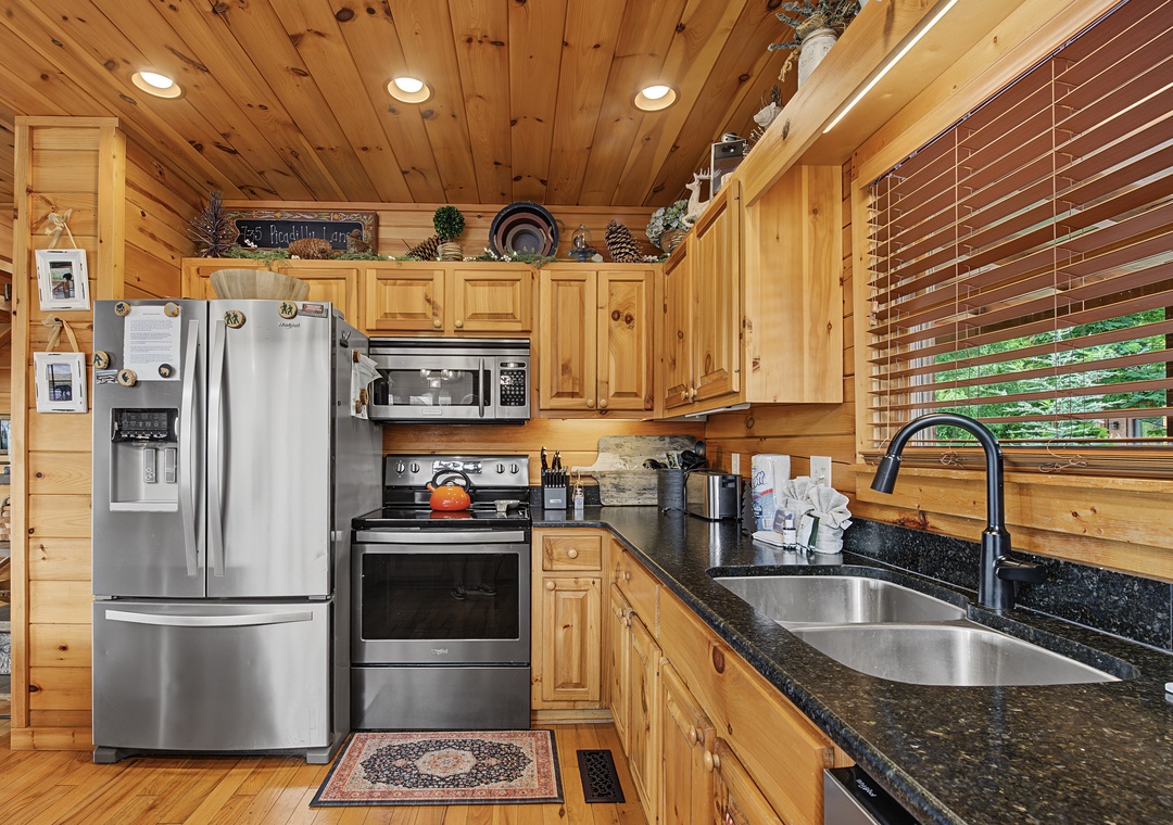 Your fully-equipped kitchen features warm wood cabinetry, stainless steel appliances, and granite countertops—perfect for preparing meals together during your mountain getaway.