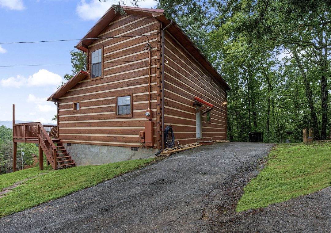This charming log cabin awaits your arrival, nestled among lush greenery with mountain views and convenient parking. The two-story structure features classic wood siding and a spacious deck perfect for outdoor relaxation.