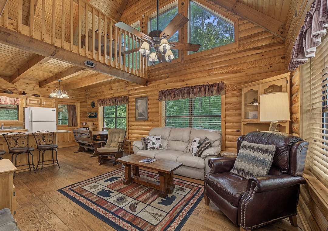 Relax in this warm, sunlit cabin with soaring wood ceilings, a cozy leather armchair, and views of leafy greenery. Your perfect rustic retreat awaits.