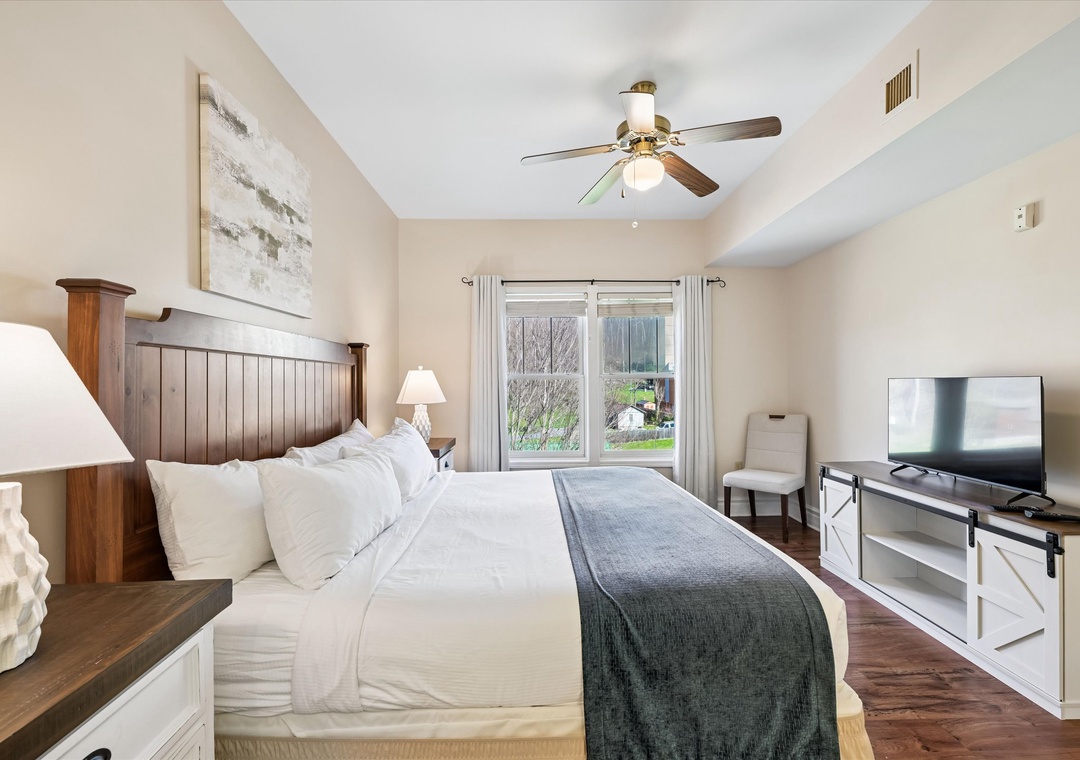 Unwind in your cozy bedroom featuring plush bedding, warm wood accents, and gentle ceiling fan for perfect comfort.