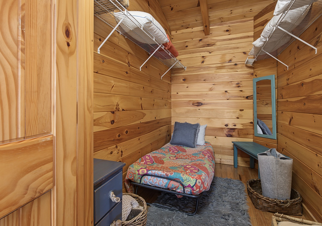 Cozy sleeping quarters feature rustic wood paneling, a comfortable bed with vibrant linens, and charming vintage touches that create your peaceful mountain retreat.
