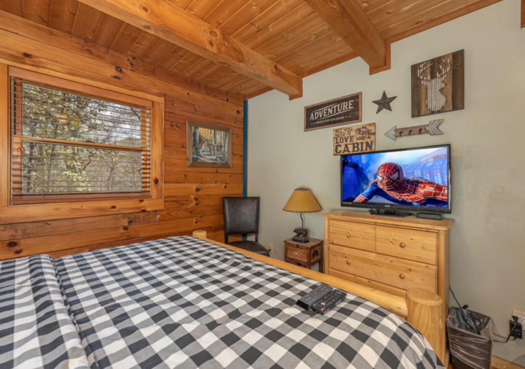 Unwind in your cozy cabin bedroom with rustic wood beams, soft plaid bedding, and a peaceful view of the surrounding forest through your window.