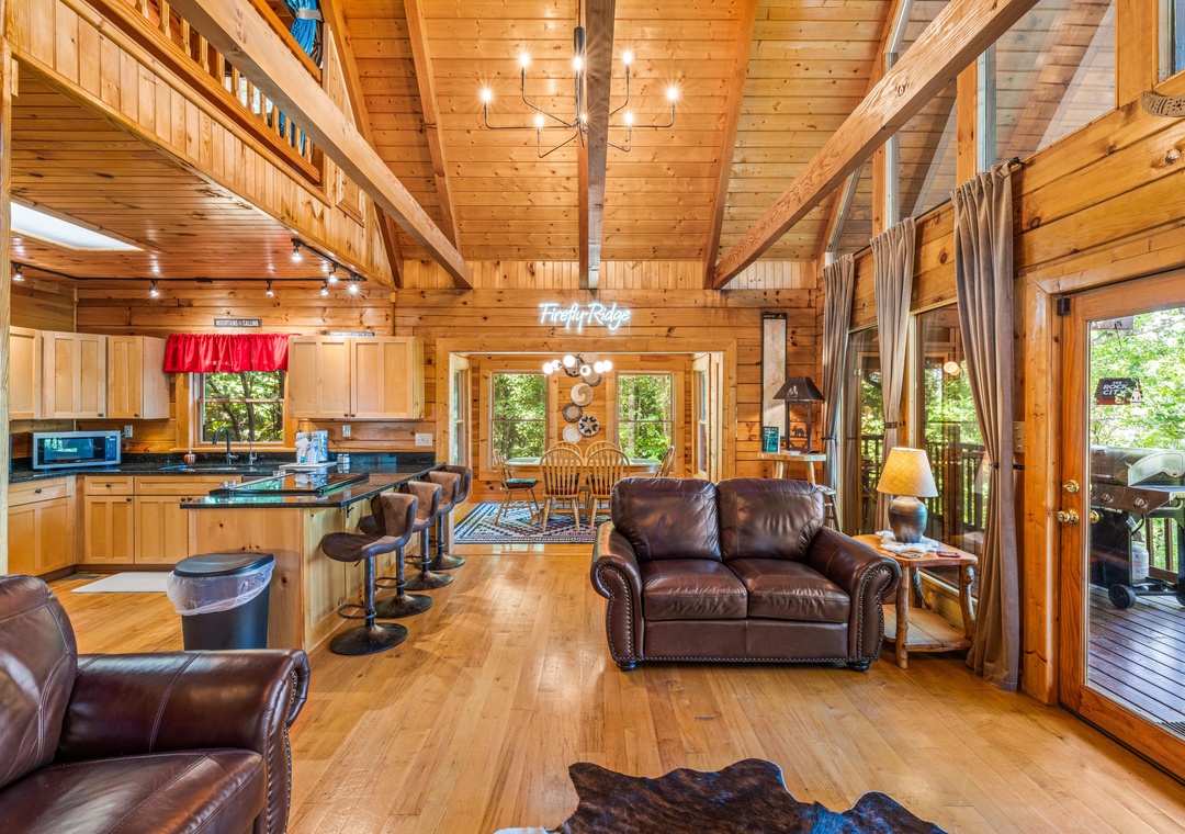 Step into your mountain retreat where soaring timber beams frame rich leather seating, a full kitchen invites gathering, and forest views surround your private escape.