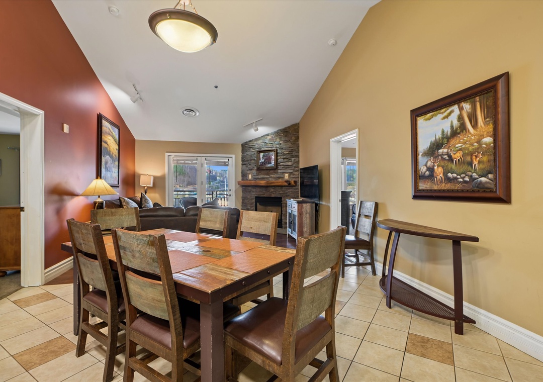 Gather around your spacious dining table for memorable meals while enjoying the cozy fireplace and mountain-themed artwork that creates a warm, inviting atmosphere.