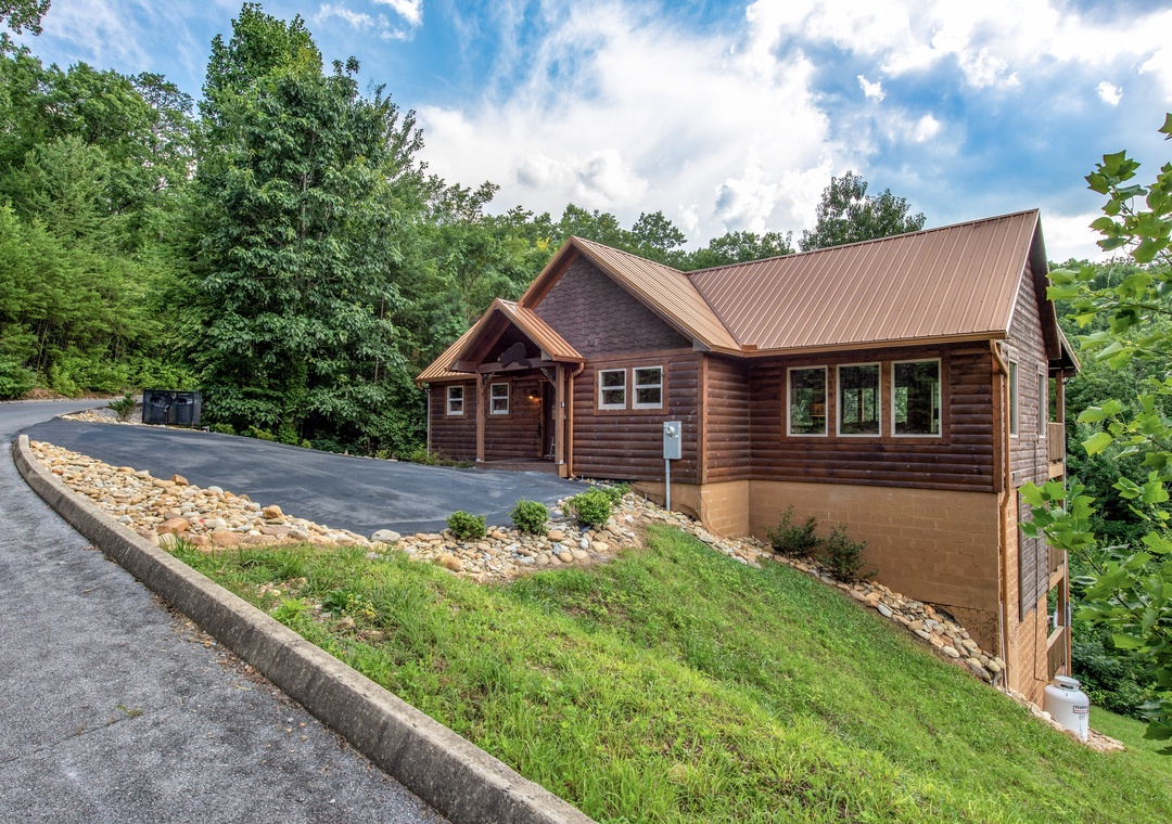 This inviting log cabin is nestled among lush green trees, offering a peaceful mountain retreat with thoughtful landscaping and easy paved access.