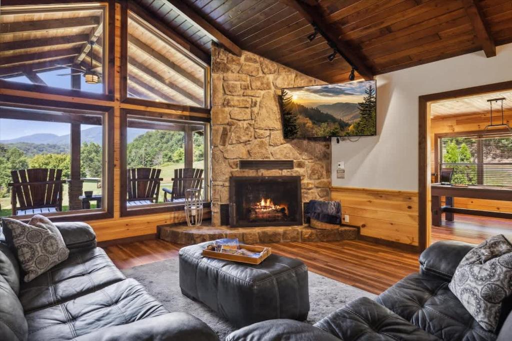 Sink into plush leather seating by your glowing stone fireplace and gaze out at mountain meadows framed by towering windows—your peaceful mountain retreat awaits.