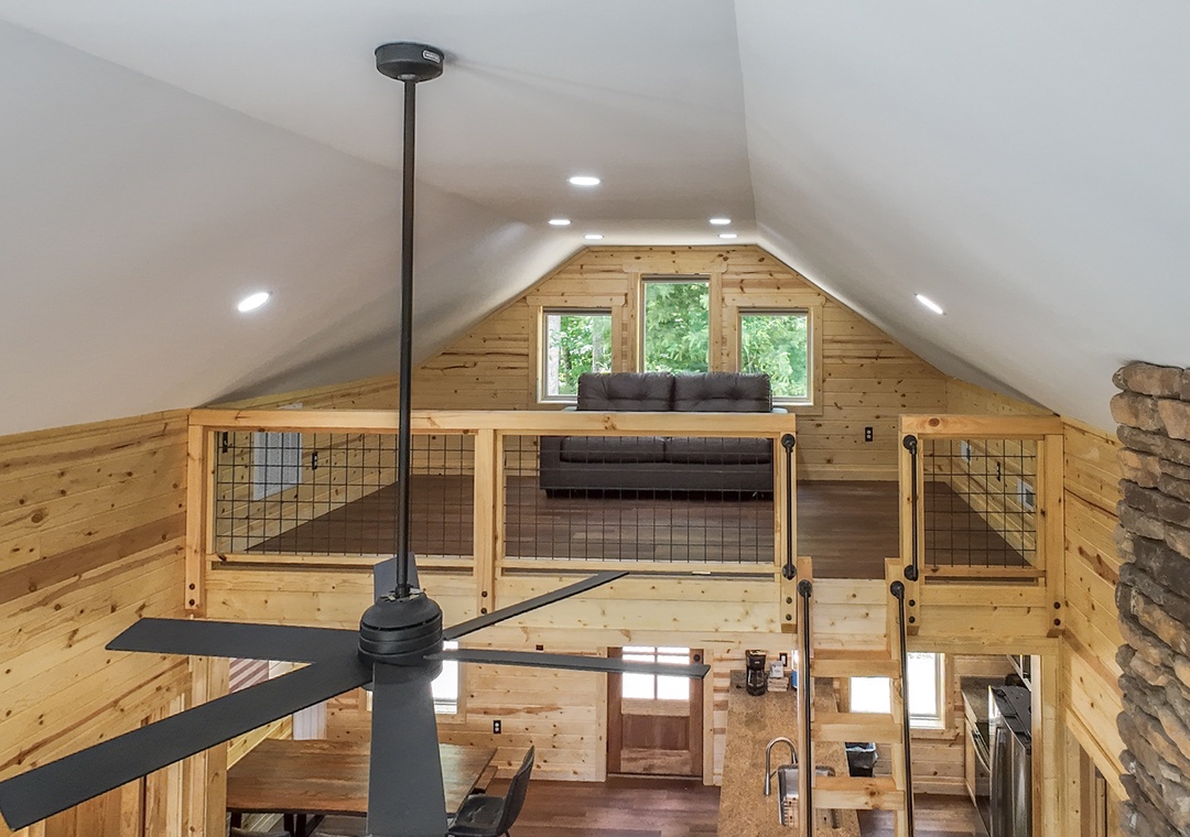 Soaring vaulted ceilings and warm pine walls create an airy, inviting retreat where natural light pours through loft windows overlooking your peaceful escape.