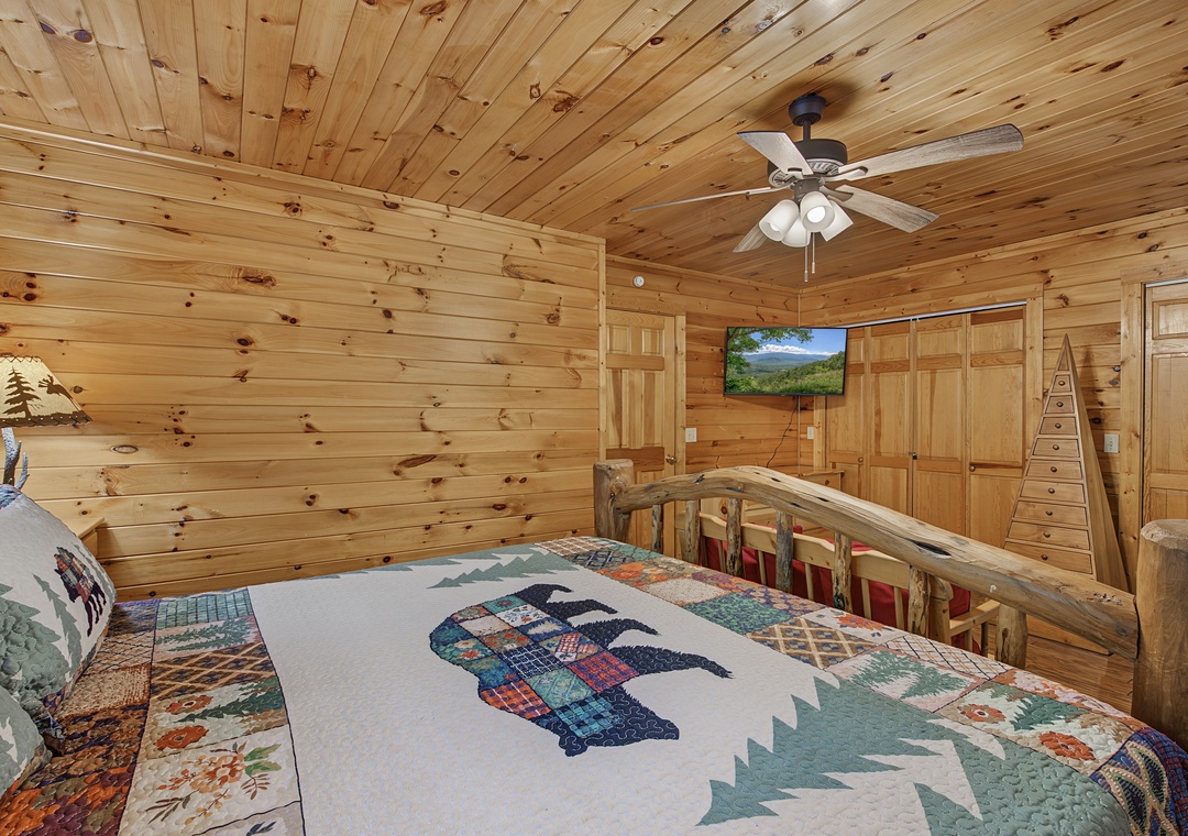 Unwind in this cozy cabin bedroom, where warm pine walls and a rustic log bed frame create your perfect mountain retreat. Gaze at scenic views on the TV after a day of exploring.