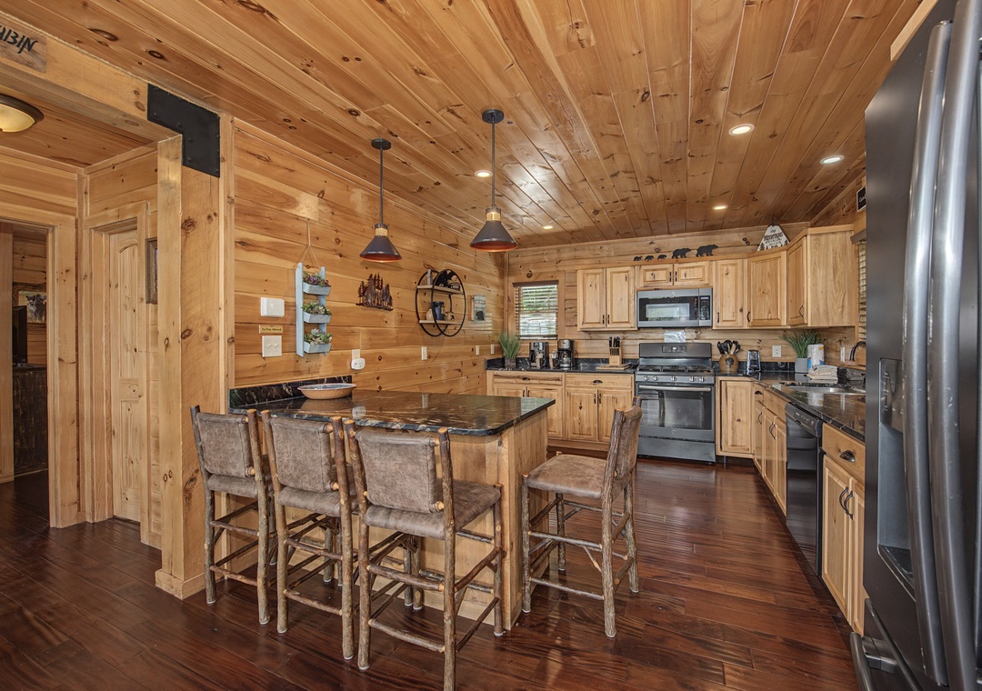 Gather around the rustic island in this warm, fully-equipped kitchen where pine walls and modern appliances blend charm with convenience for your mountain getaway.