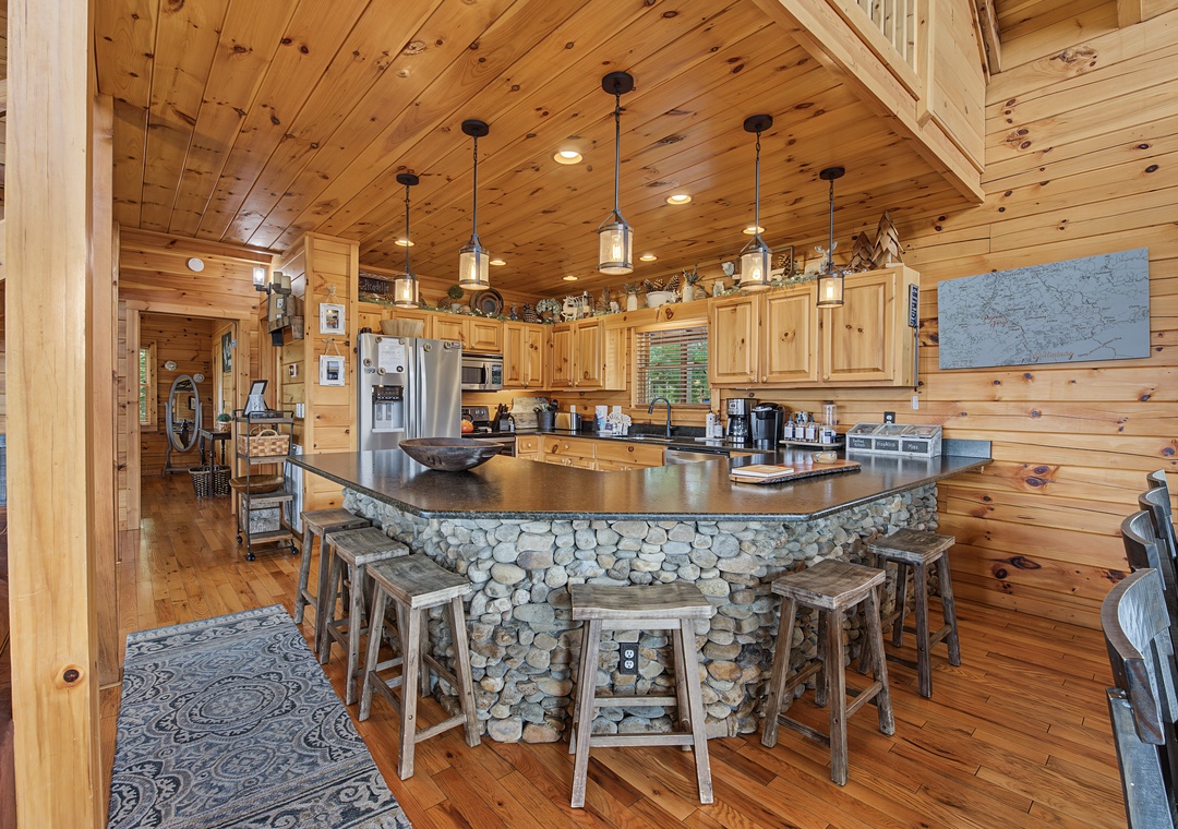 Your rustic mountain retreat features a stunning stone-clad island with bar seating, premium appliances, and warm wood finishes that create the perfect gathering spot for memorable meals together.