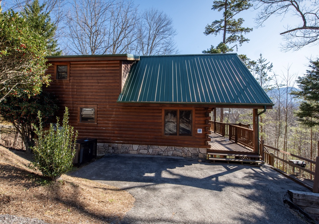 Charming log cabin nestled among tall pines with convenient parking and covered entrance deck.